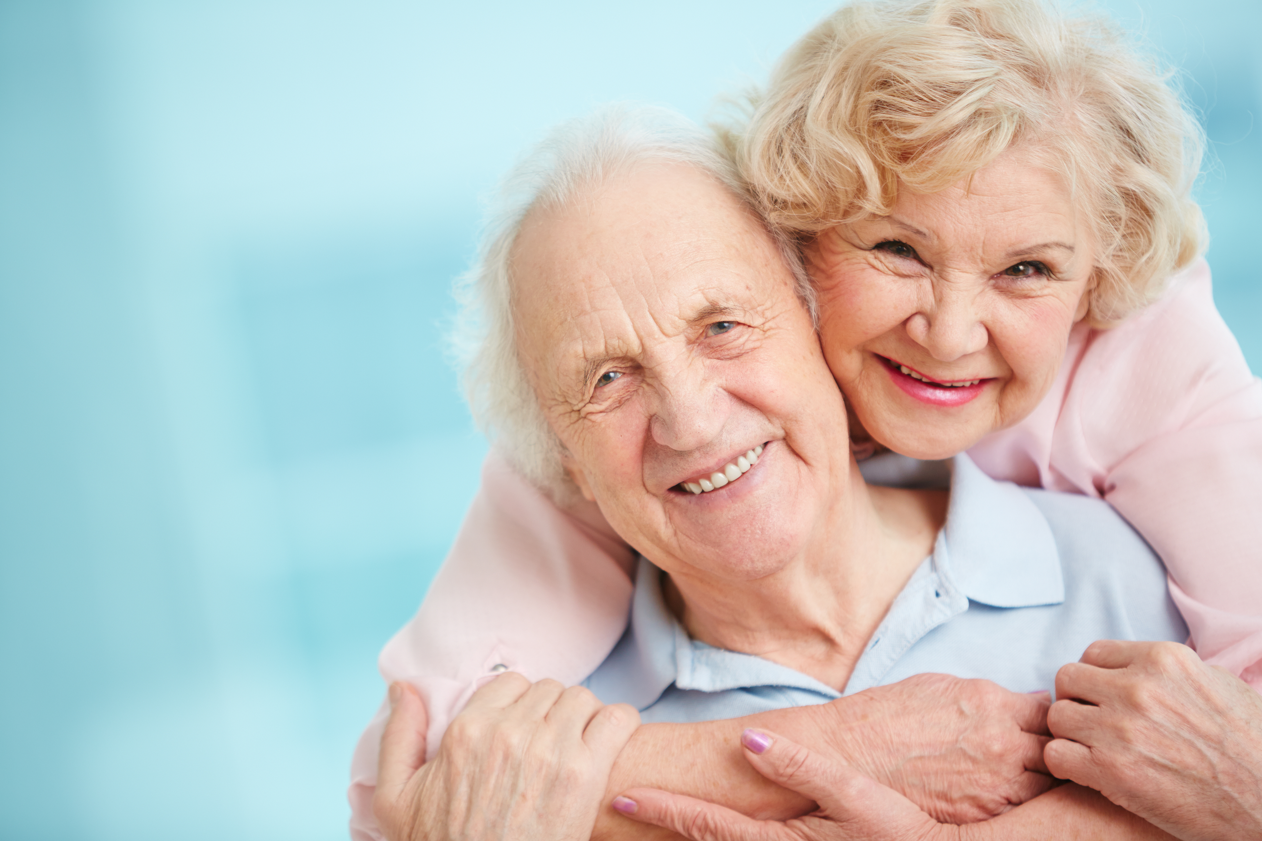 Happy and affectionate elderly couple looking at camera with smiles