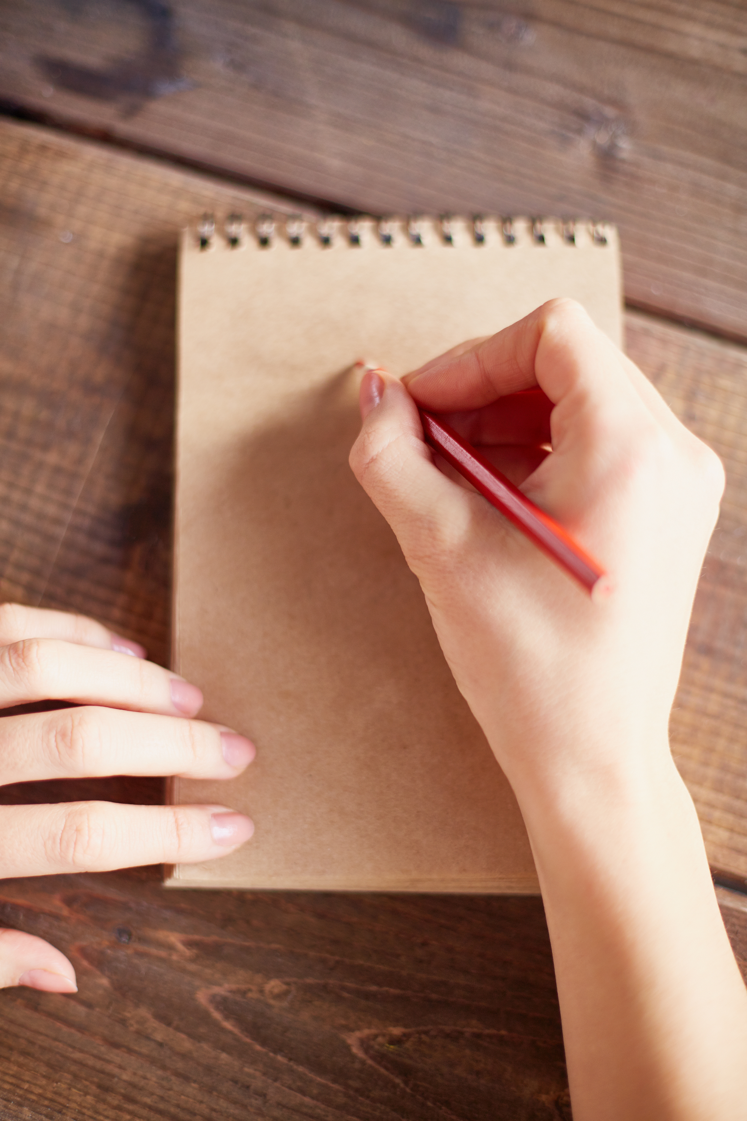 Human hand with pencil making notes in notepad